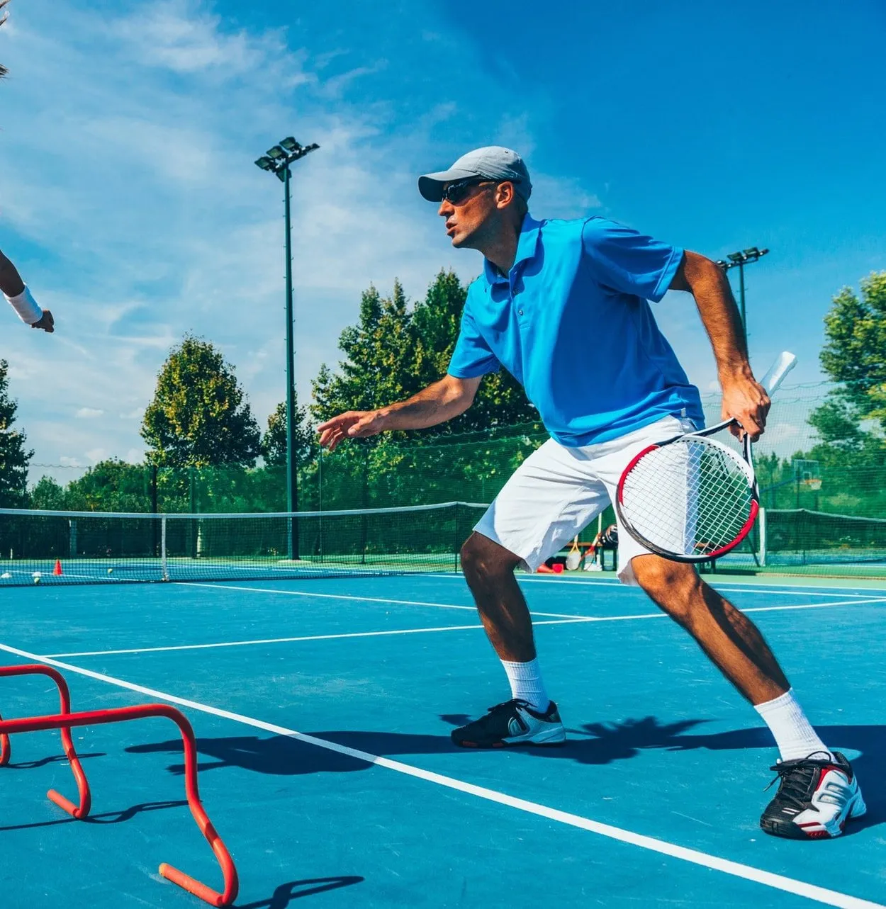An adult player moving into position during a tennis session on an outdoor hard court