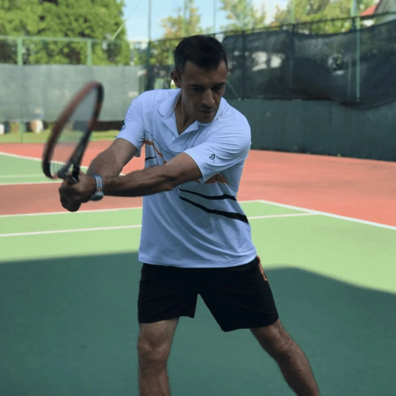 An adult player mid-backhand during a Pure Sport tennis lesson in Singapore