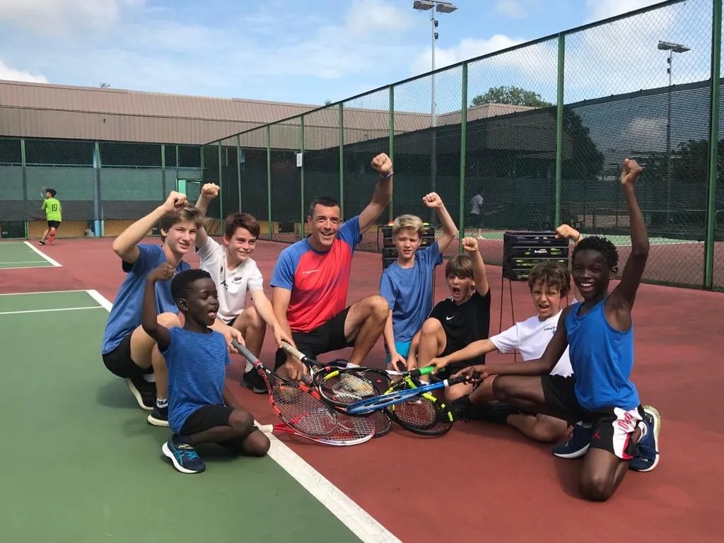 Campers celebrating with their coach at the end of a holiday tennis camp session