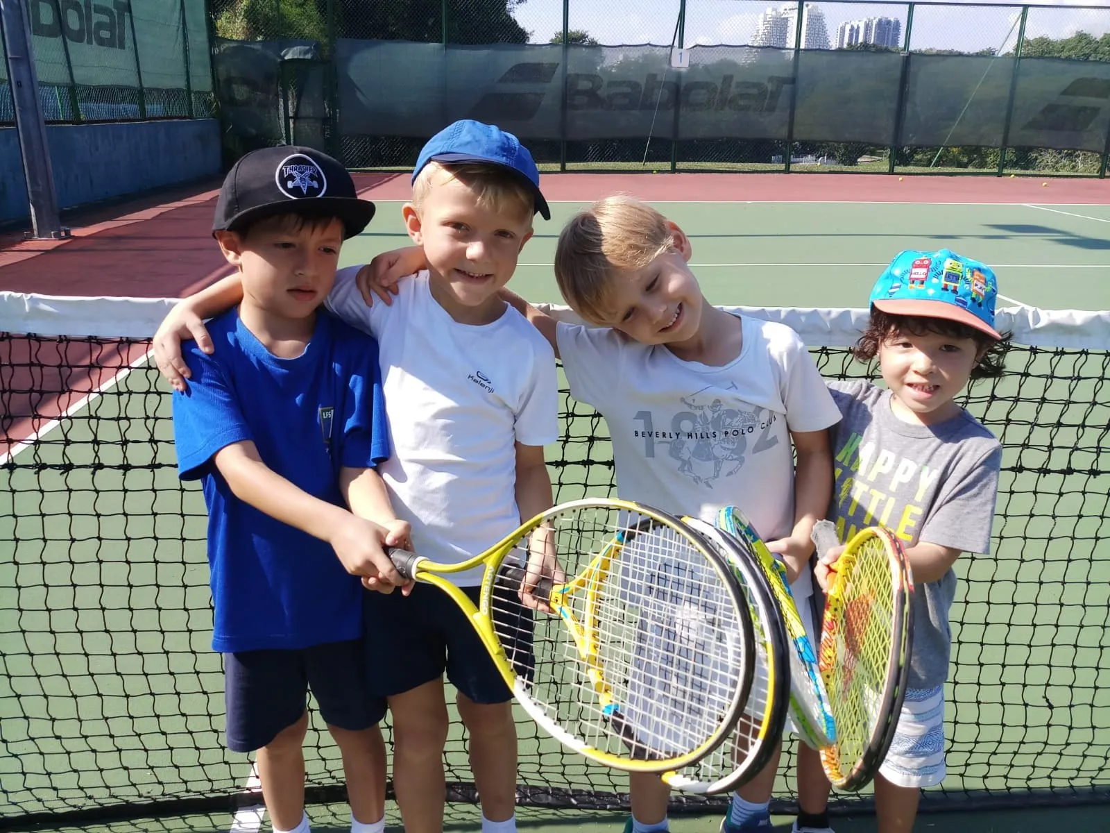 Young players arm in arm at the net during a Pure Sport holiday tennis camp