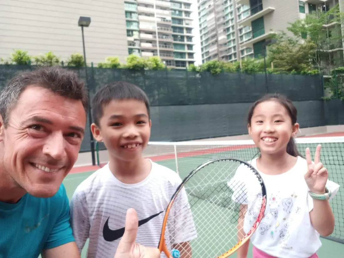 Smiling kids with their tennis coach in Singapore