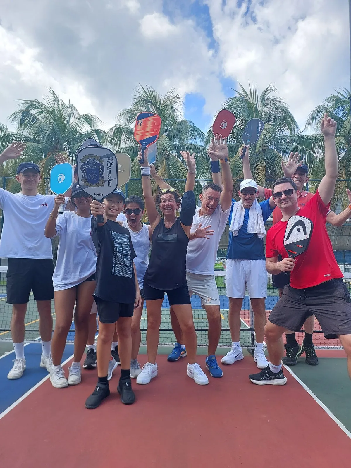 Mixed-age pickleball group with their paddles after a Pure Sport session