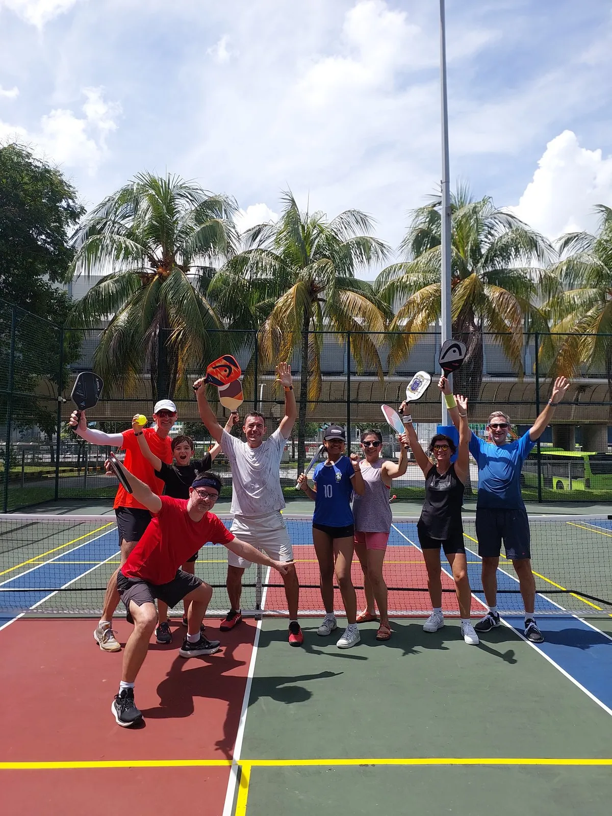Pickleball group celebrating with paddles raised on court in Singapore