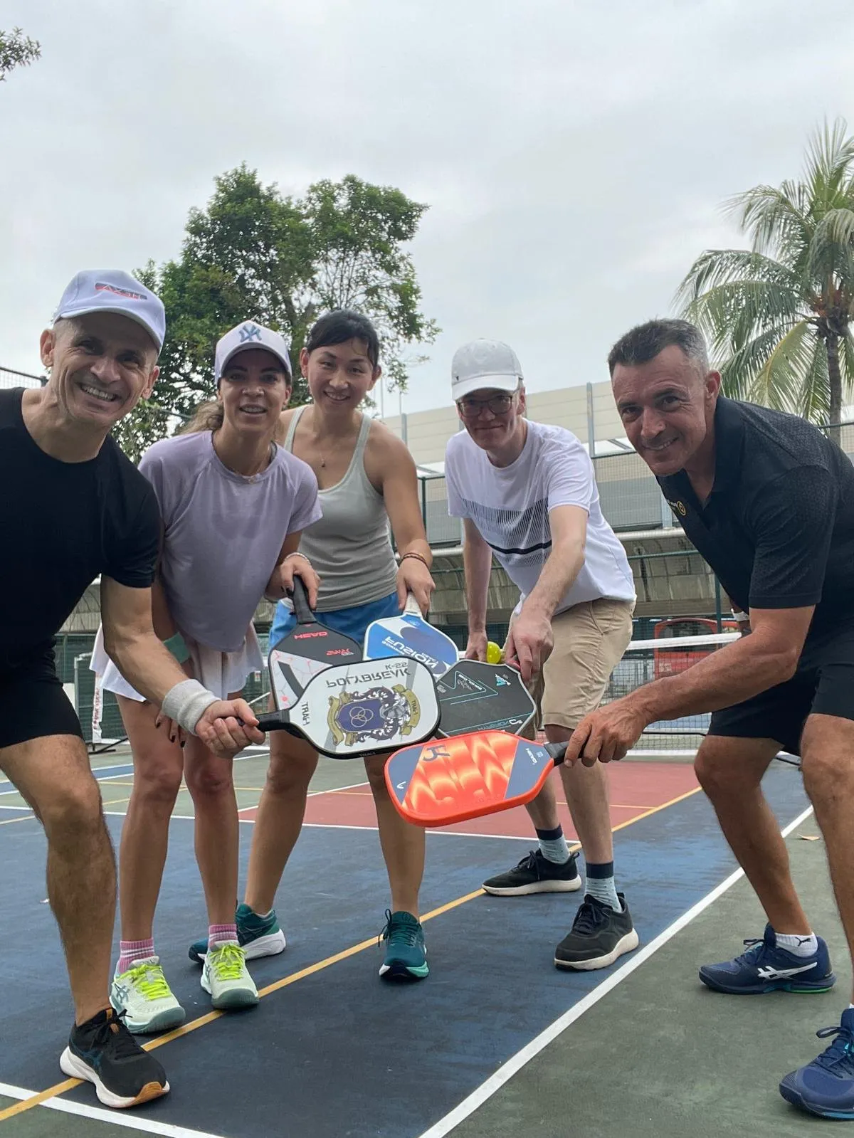 Five pickleball players gathered around their paddles at the net