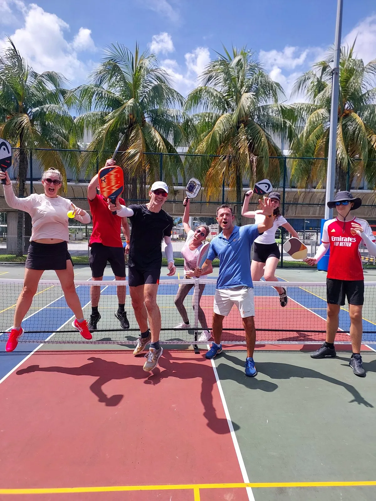 Players jumping for a group photo after a Pure Sport pickleball session