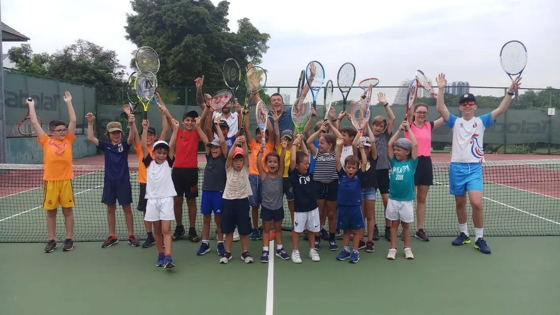 Teenage campers raising their racquets together on a Singapore court
