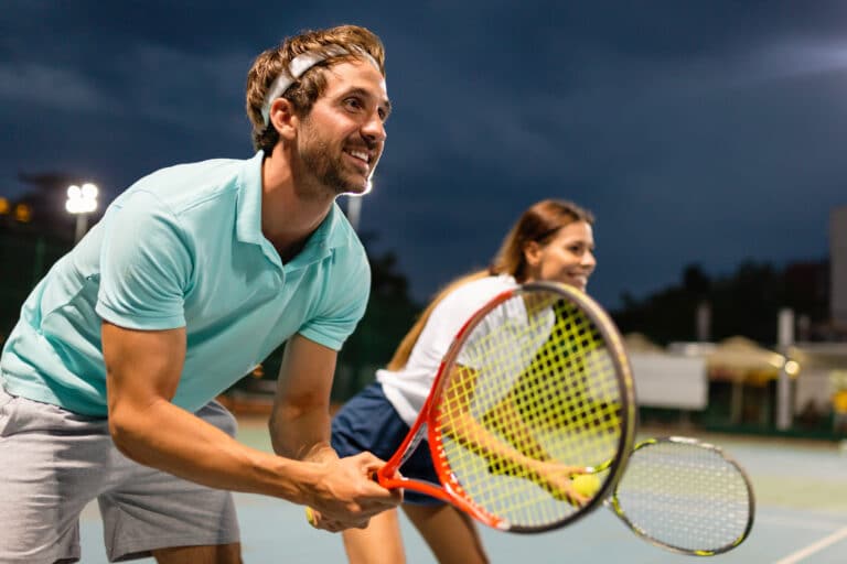 Tennis sport people concept. Mixed doubles player hitting tennis ball with partner standing near net